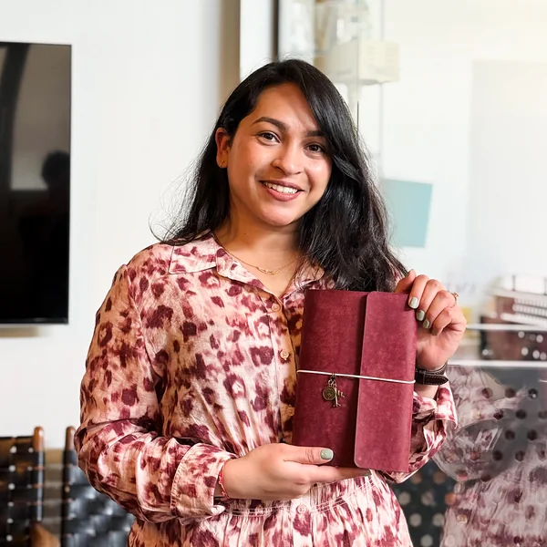 A smiling guest holding up her burgundy suede journal