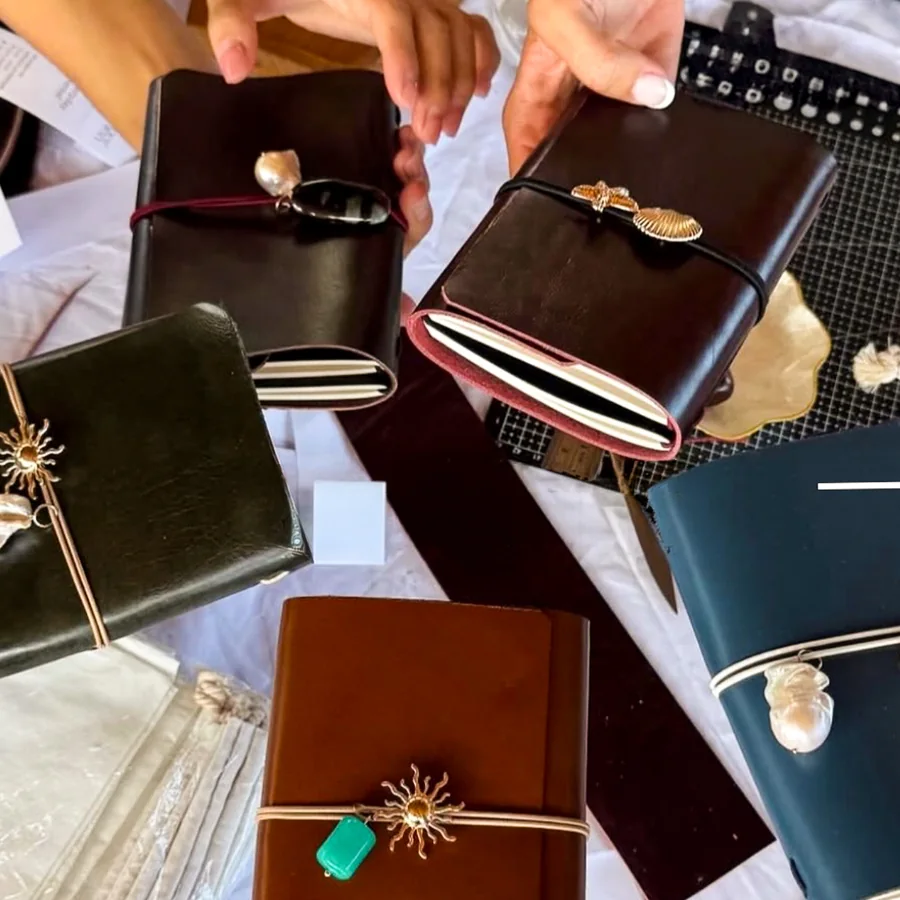 A group holding up their finished leather journals in black, brown, burgundy and navy